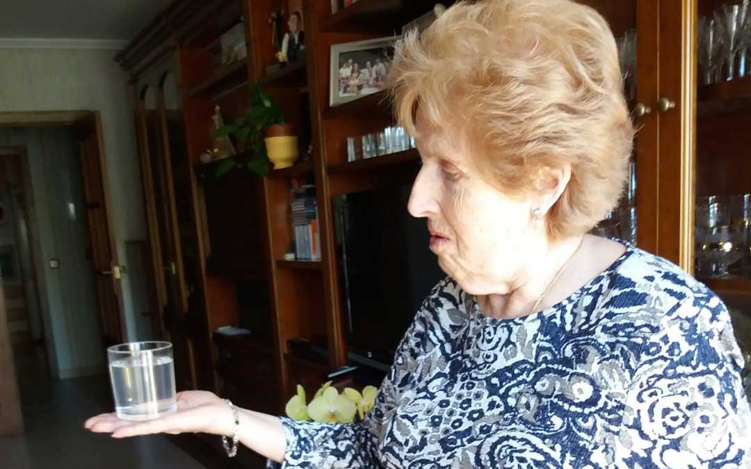 La vecina de Albalate, Rosario Larrodé, muestra un vaso de agua turbia esta semana en su casa de Albalate. ANDRÉS SERRANO