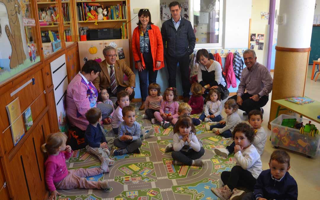 El Justicia, agachado, en la escuela infantil con los niños y niñas de la localidad