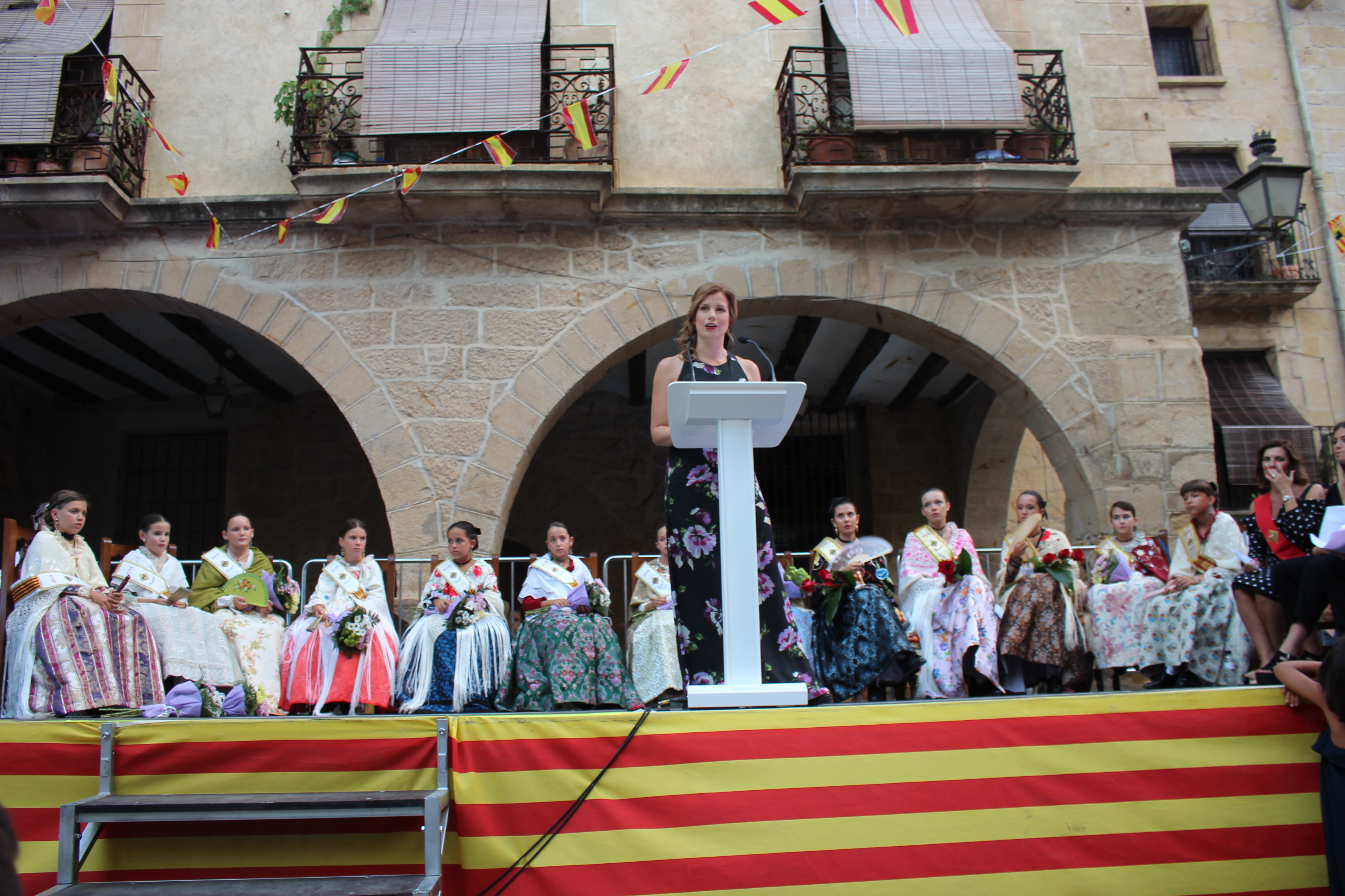 La pregonera, Eva Defior, leyendo el pregón con las reinas y la alcaldesa en el escenario. Foto: L. Castel