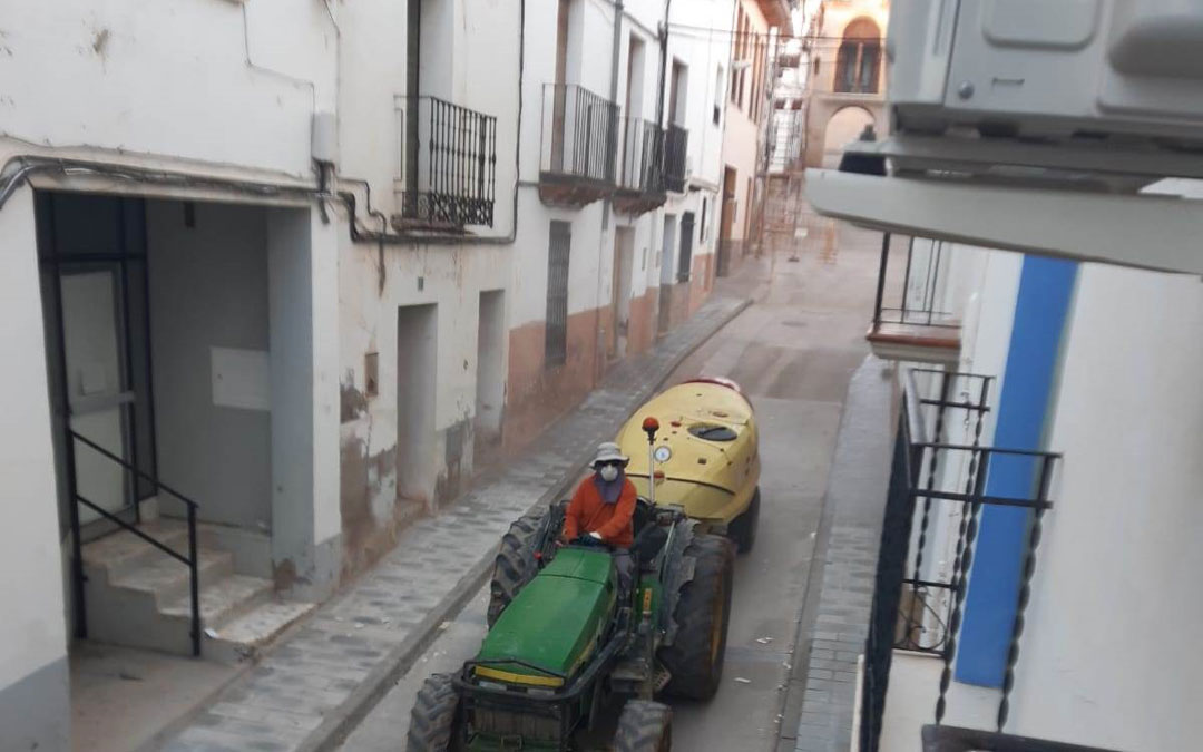 Uno de los agricultores, en proceso de desinfección de Urrea de Gaén con el arco de San Roque al fondo. / Ayto. Urrea