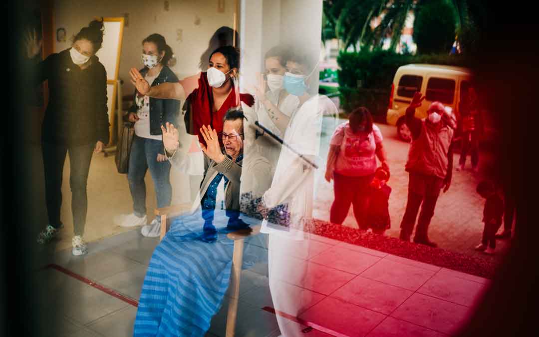 Una mujer emocionada saludando a su familia desde el interior de la residencia Adolfo Suárez de Caspe. Imagen: Cesáreo Larrosa.