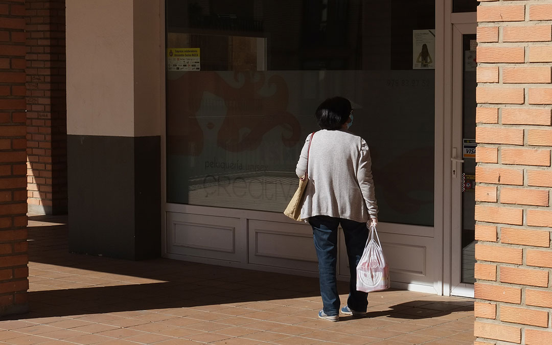 Una mujer en Alcañiz delante de un establecimiento cerrado después de salir a hacer la compra./ A.M.