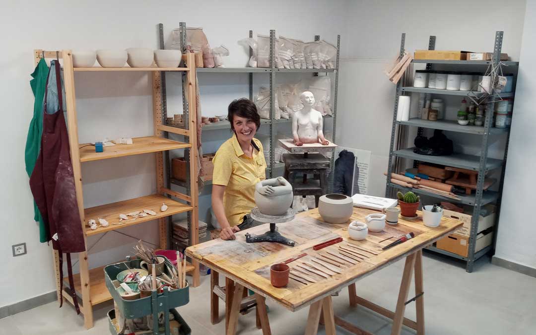 Malia Pérez, en su taller-laboratorio en Oliete con sus creaciones. Al fondo, el boceto de ‘Moradoras de la tierra’. / Archivo personal