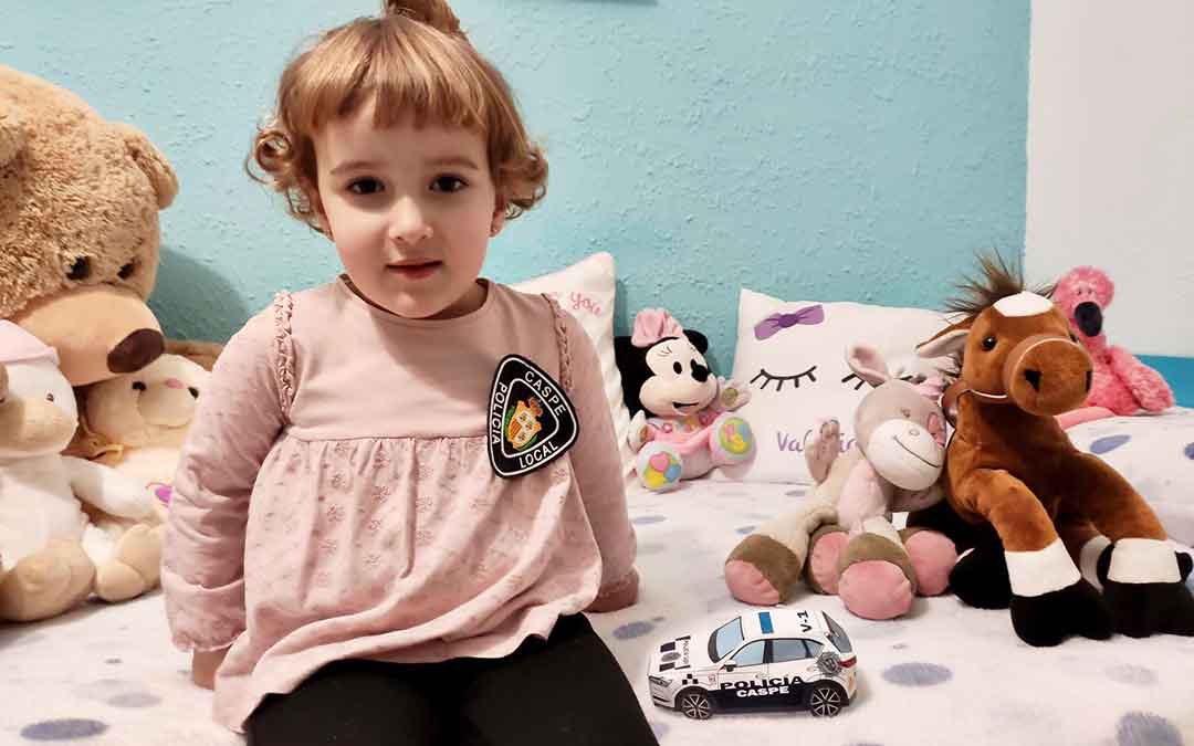 Niña con su coche de Policía Local de Caspe hecho de papel.