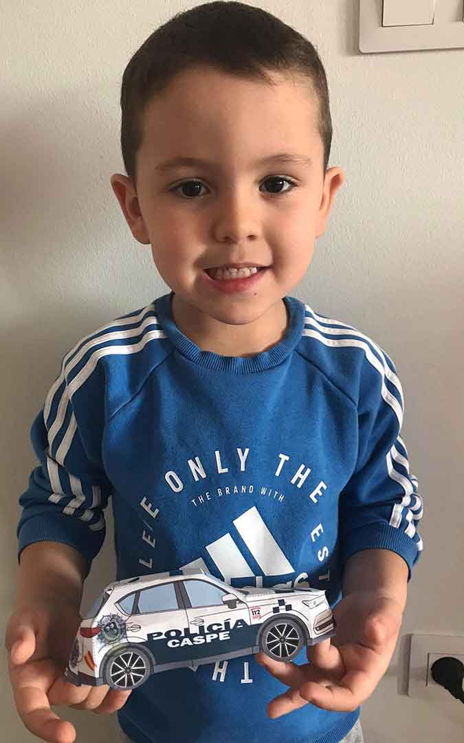 Niño con su coche de Policía Local de Caspe hecho de papel.