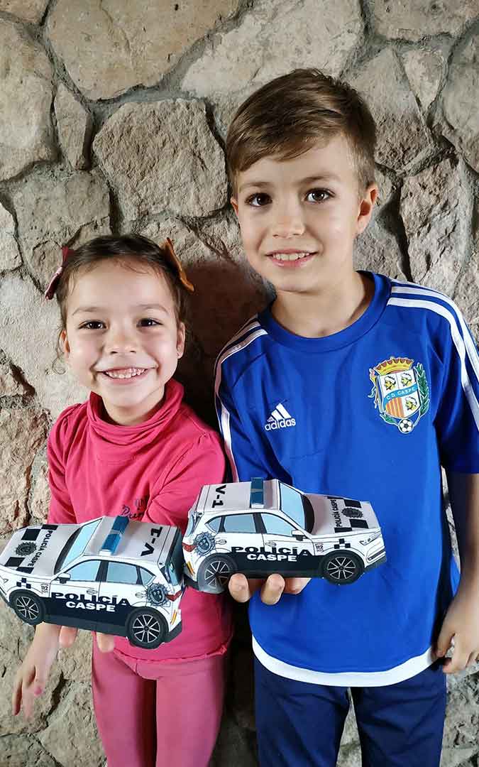 Niños con sus coches de Policía Local de Caspe hechos de papel.