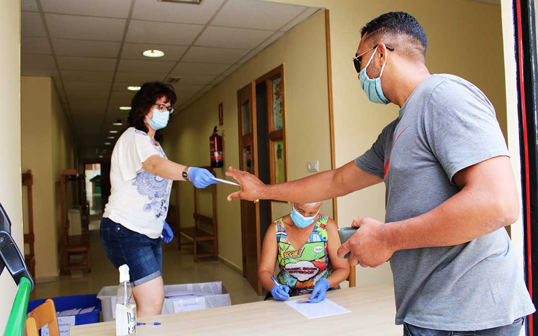 Una funcionaria municipal entrega un sobre con mascarillas y un folleto de recomendaciones a un vecino de Caspe./ Pilar Sariñena