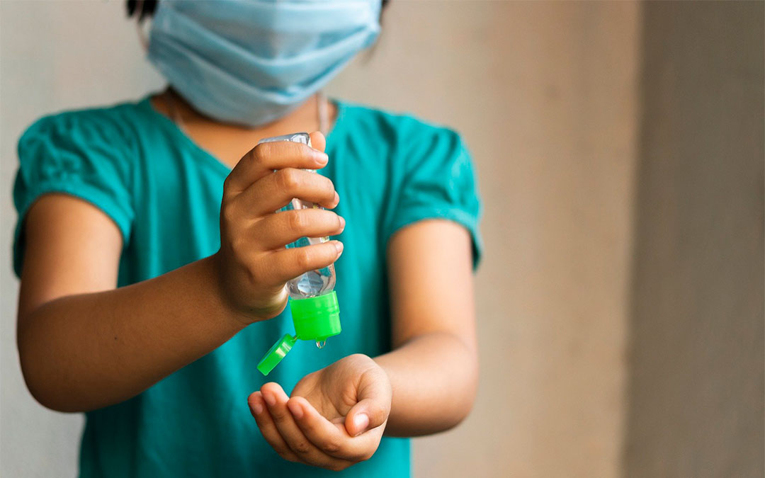 Una niña con mascarilla y gel hidroalcohólico./ Pixabay