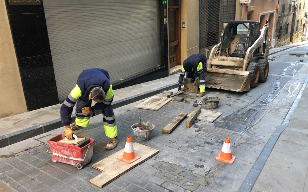 Dos trabajadores sustituyendo los adoquines de la calle Mayor / L. Castel