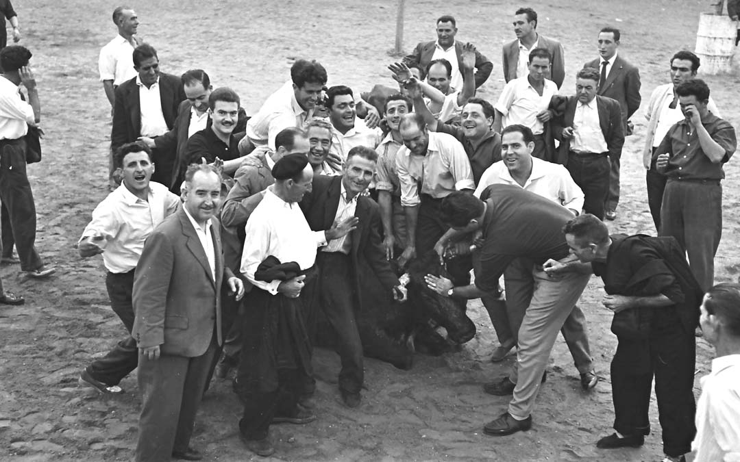 Varios hombres sujetan a una res en el ruedo en el conocido como Día de la Comisión de 1961