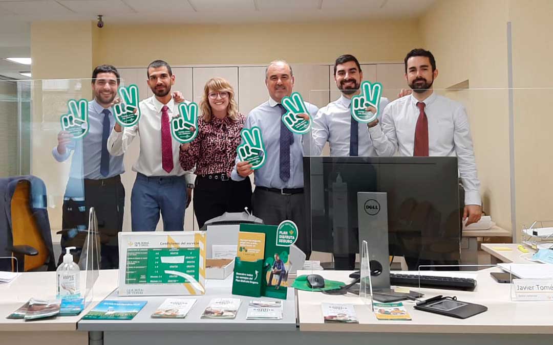 Trabajadores de la oficina de Alcañiz, este jueves, con la imagen identificativa del día solidario / Caja Rural