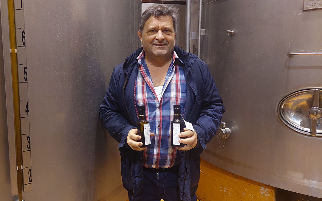El gerente de la cooperativa del Mezquín junto a unos tanques de aceite de oliva y dos botellas de Reales Almazaras