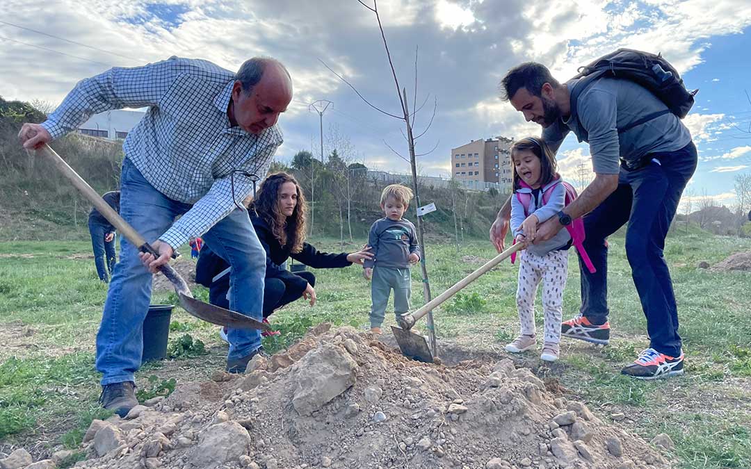 Javier Escorza, de la asociación Amigos del Río (a la izquierda) ayuda a una familia con la plantación./ M.C.