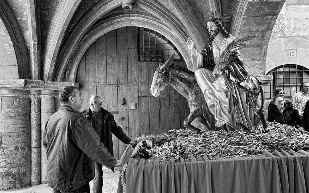 GEOGRAFÍAS DEL OLVIDO 02: Abril 2019 (Semana Santa). La ¨borriquita¨, figura que procesiona en Calaceite el Domingo de Ramos, y sus portadores hacen una pausa justo debajo de la Capilla de San Antonio,desde donde el capellán bendice las palmas y las ramas de olivo que portan los feligreses./ Santi Cogolludo
