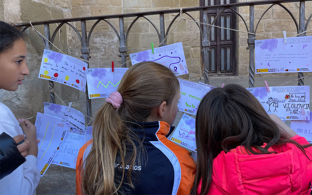 Tres estudiantes cuelgan sus mensajes en la Lonja de la plaza de España de Alcañiz./ M.C.