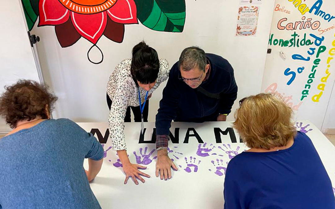 Con las nociones de la terapeuta ocupacional de ASAPME, Almudena Balaguer; Marina, Francisca y Manolo, plasman las 52 manos que representan a cada mujer asesinada este año, y que lucirán en la pancarta en la concentración en Alcañiz. Participarán usuarios de Alcañiz y Calanda. / María Celiméndiz