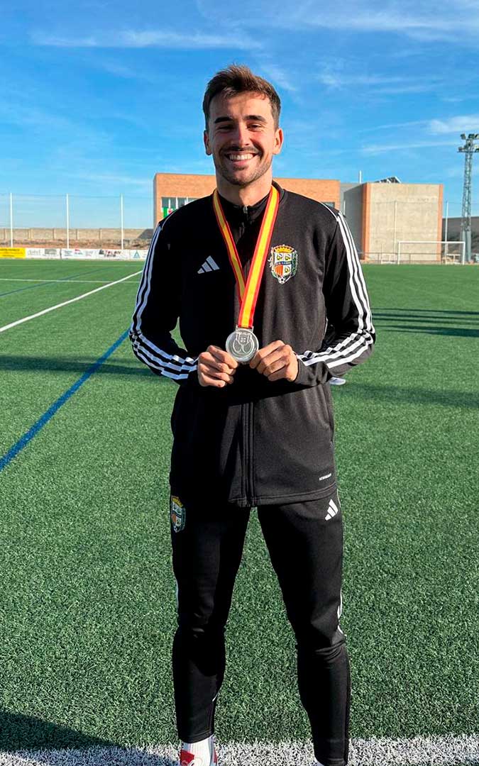 Iván Vicente, lateral derecho del C.D. Caspe, junto a la medalla de subcampeones de Copa que C.A. Osasuna regaló a la familia de Luismi. / I.V.