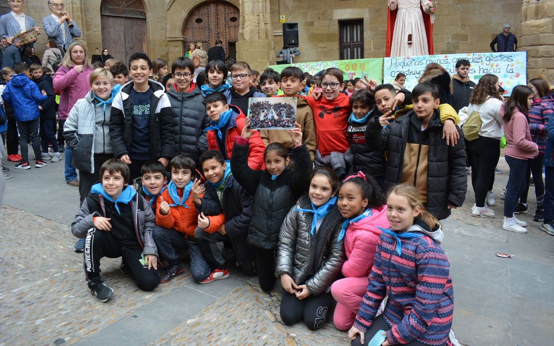 Los pequeños posando con una fotografía de la celebración del año pasando, en la que entre todos construyeron la palabra 'Paz'./ C.O.