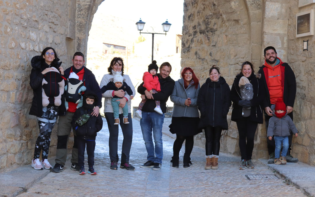 Los padres y madres sonrientes ante uno de los emblemas de la localidad, el Portal de las Monjas, donde muchos han jugado durante años y pronto lo harán sus hijos. /N.A.