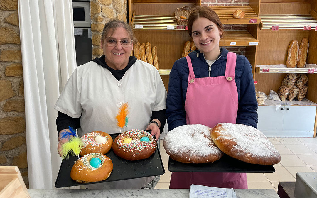 Imagen de archivo. Maribel Cano (a la izquierda) en 2024 vendiendo en la panadería Enrique Alonso de Alcañiz las «rosquetas» típicas de Lunes de Pascua. Muchos clientes también pidieron a Clara Alonso (a la derecha) tortas de Pascua./ María Celiméndiz