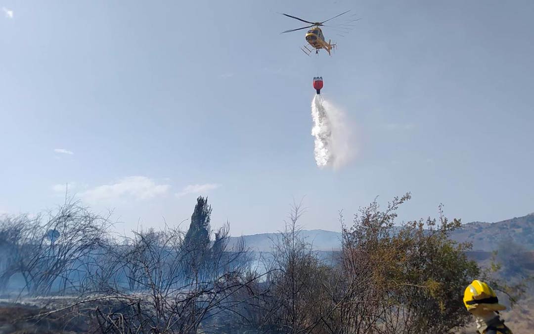Helicóptero de extinción descargando agua sobre el foco del fuego./ La COMARCA
