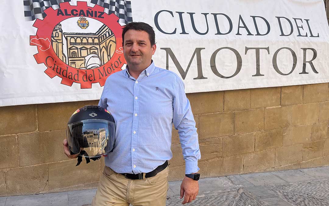 El alcalde de Alcañiz y vicepresidente de Motorland, Miguel Ángel Estevan, delante de la lona colocada en la Lonja de la plaza España con el casco de su moto, con la que suele circular por la ciudad./ L. Castel