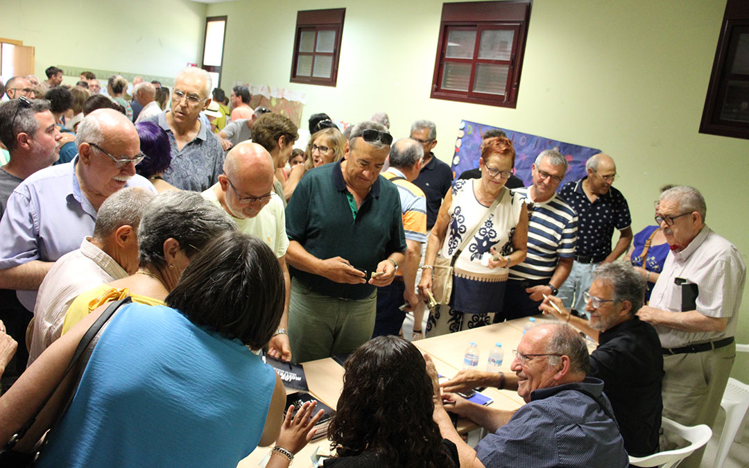 Esteban Vidal sonríe rodeado del público que llenó el aula donde estudió, ahora ludoteca. A su lado, Moragriega y Bello. / B. Severino