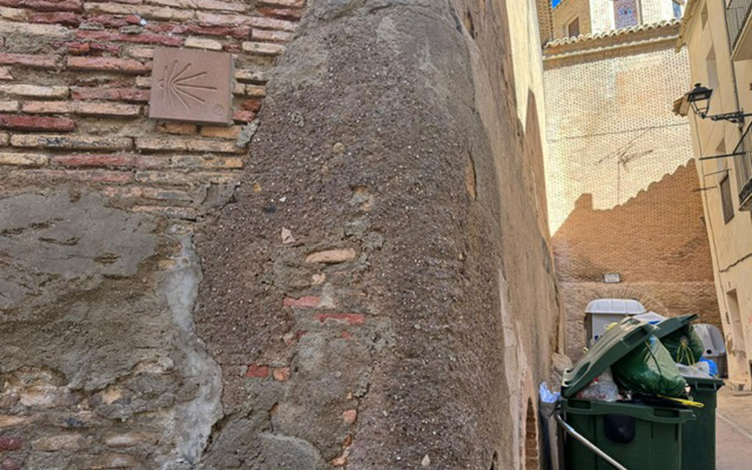La pared de la iglesia con la señal del Camino de Santiago y contenedores. / L.C.