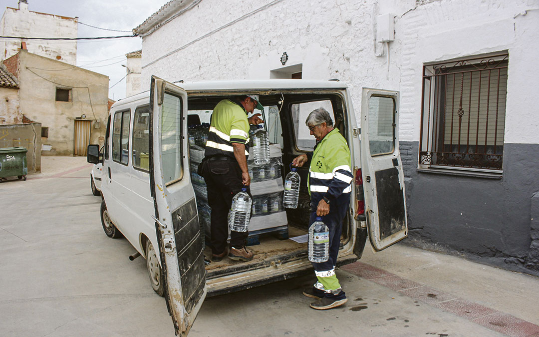 Dos trabajadores de la brigada de Samper repartiendo las garrafas puerta a puerta. / Laura Castel