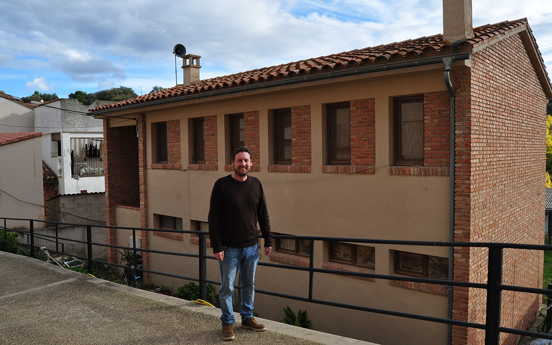 El alcalde de Torre de Arcas, Luís Lasmarías, junto al edificio de las escuelas y que albergará la vivienda de alquiler./ J.L.