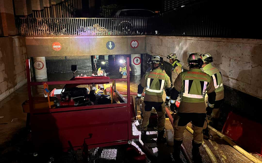 Un grupo de bomberos de Caspe colaboran en la retirada del agua en un garaje./ G.L.