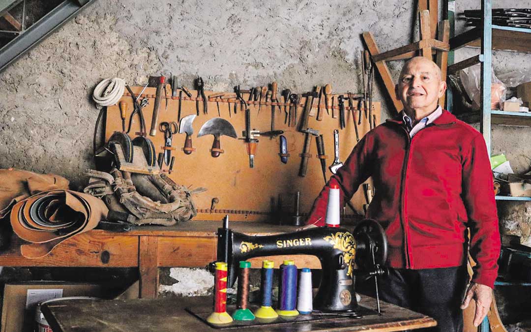 Enrique Vallespí, con algunas herramientas y pieles que conserva de la guarnicionería en Nonaspe y su inseparable máquina de coser. / Alba Zurita