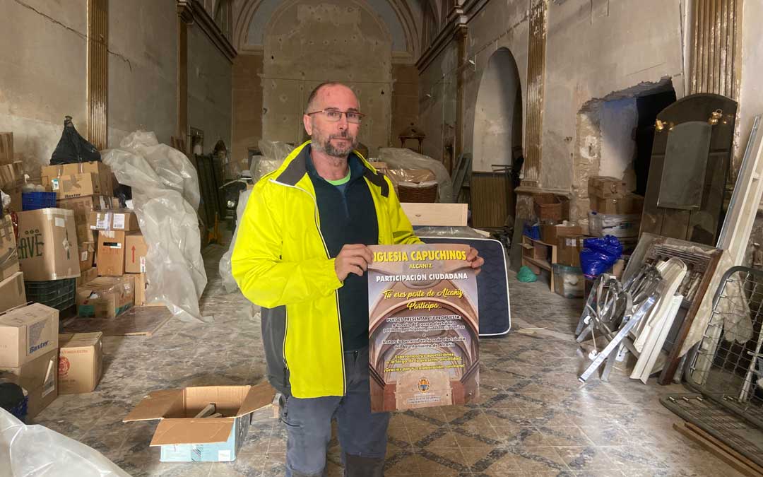 Carlos Andreu posa con uno de los carteles en la iglesia de Capuchinos de Alcañiz./ M.M.R.