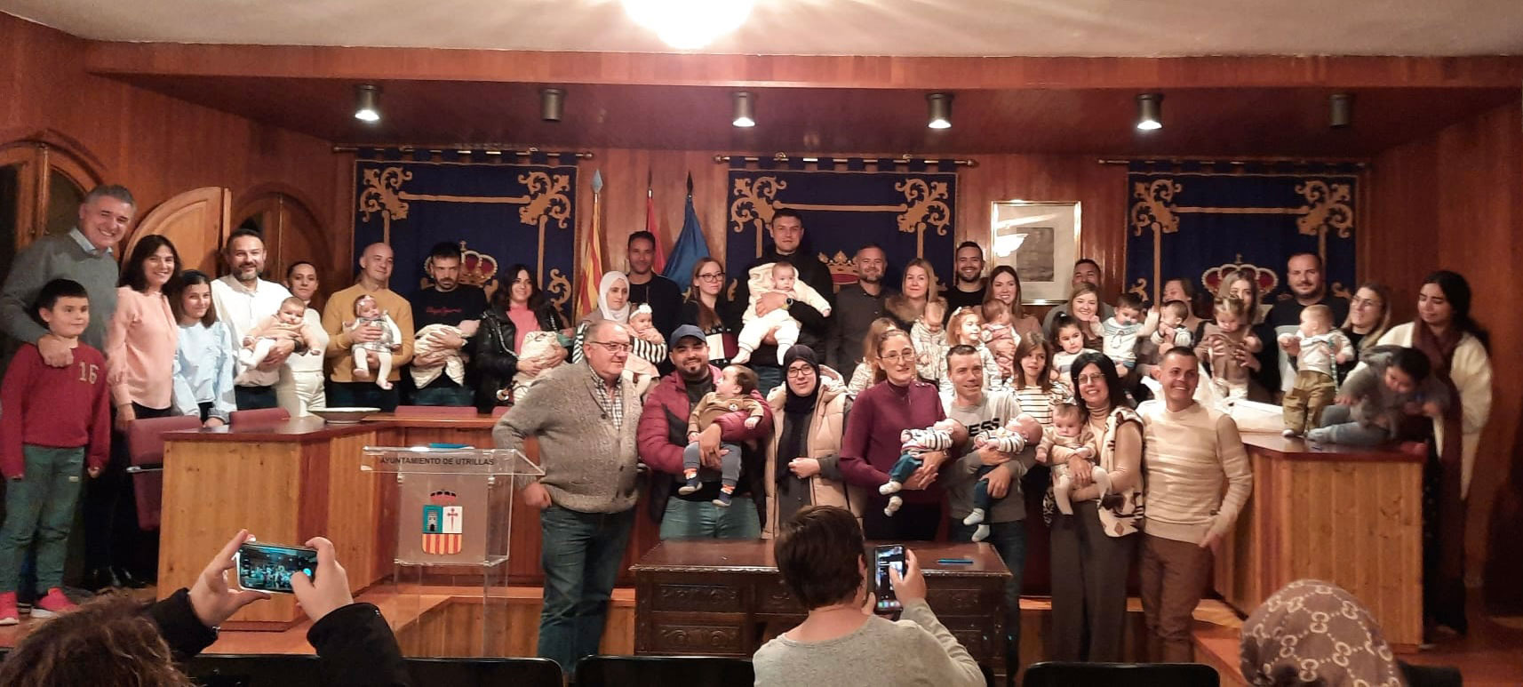 Foto de familia de todos los padres junto a los bebés y las autoridades en la entrega de los cheques de 1.400 euros para cada nuevo niño. / Ayto. Utrillas