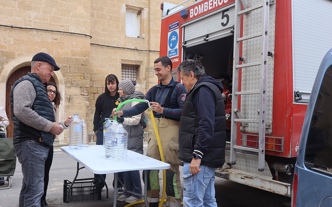 Los Bomberos de la DPT de Alcañiz en el segundo día de llenado de agua potable de garrafas en Valdealgorfa. / Alba Zurita