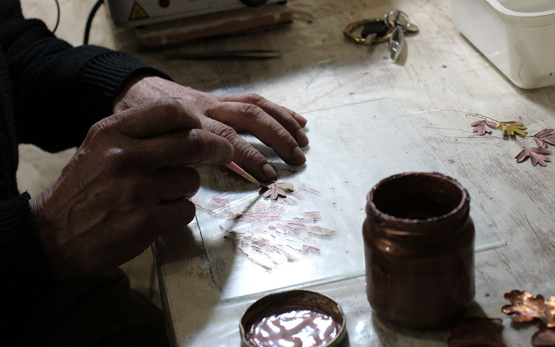 Aplicando el barniz con cobre a la hoja para sumergirla en la solución. / B. Severino