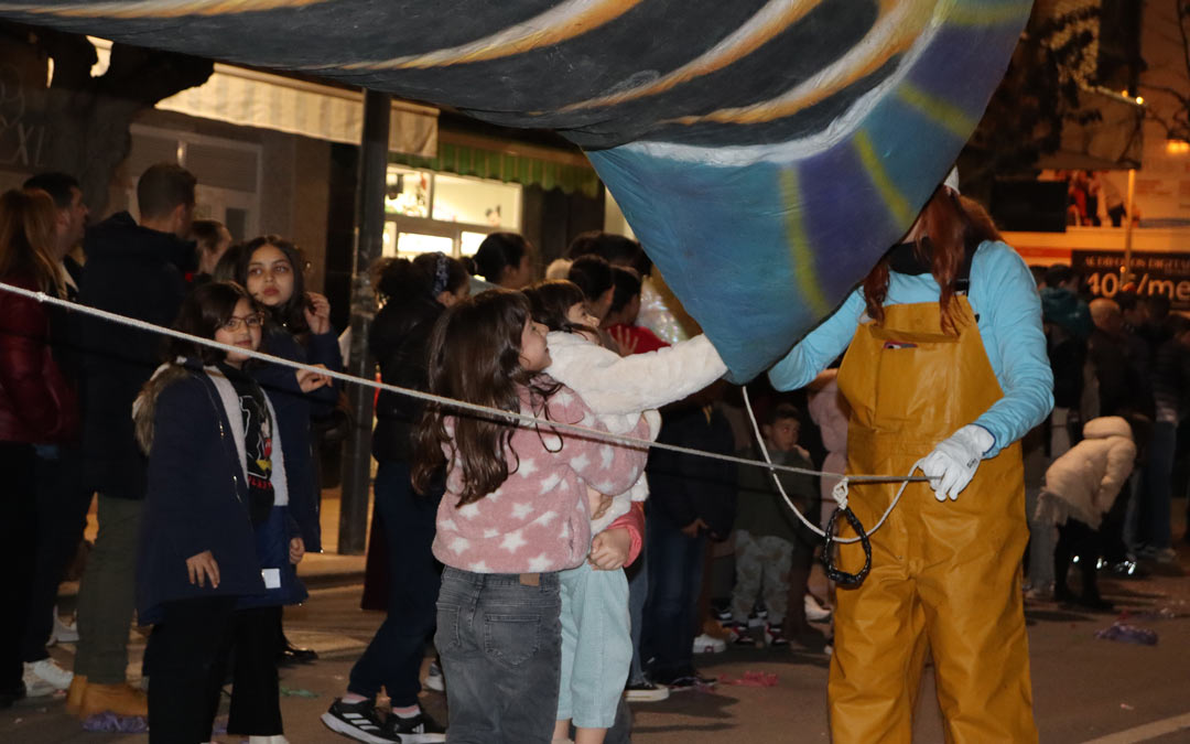 Una niña ayudando a que otra pudiese tocar un pez gigante durante la cabalgata./ Sandra Jiménez