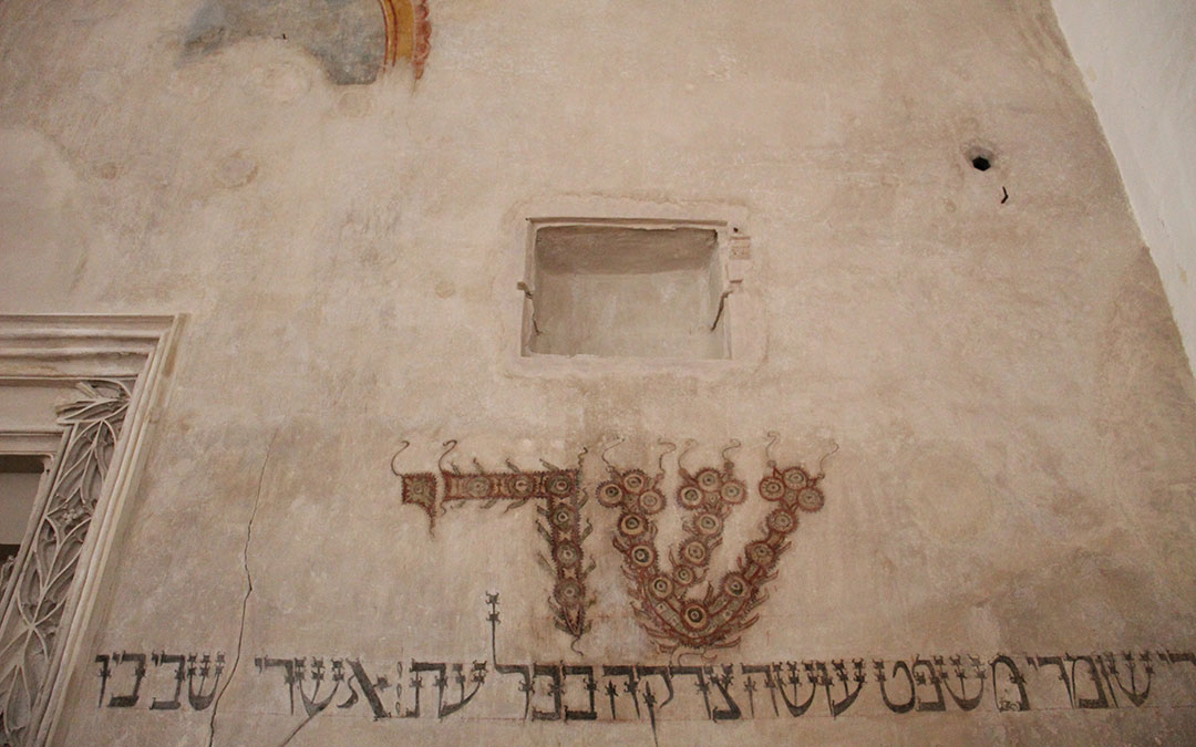 Las letras que se atribuyen al salmo 106.3 y arriba a la derecha, el orificio hexagonal con un clavo del siglo XV. El hueco pertenece a la hornacina en la que se guardaba el shofar. / B. Severino
