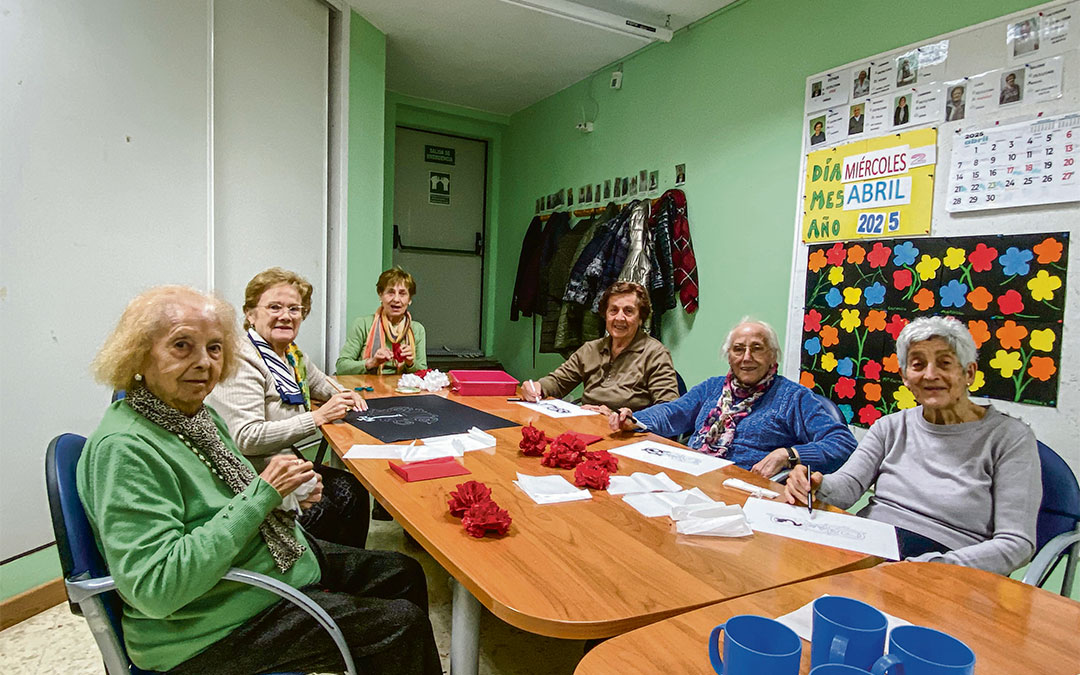 Parte de los usuarios junto a los claveles rojos y blancos, que han elaborado para el mural en motivo de su nombramiento esta Semana Santa. / A.Z