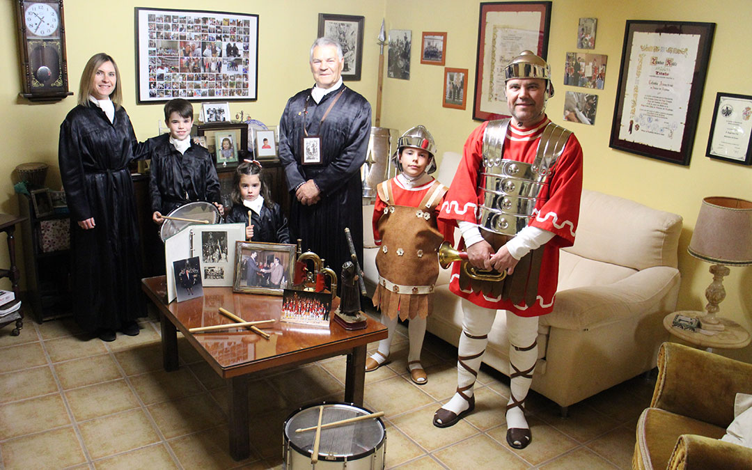Ángel Soro, con túnica y el escapulario que le identifica como parte de la organización en las procesiones, rodeado de recuerdos en la bodega junto a Marián Soro y su hijo Pablo Querol; la pequeña Carlota Soro, y Alonso y Diego Soro, tercera y cuarta generación de alabarderos. / B. Severino