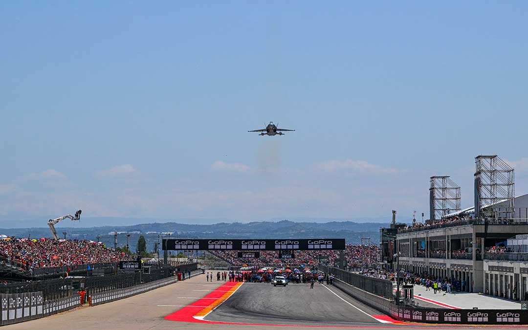 Momentos previos a la salida de la carrera de MotoGP con la grada 1 y la tribuna llena. En el cielo, un starfighter que ha realizado unas demostraciones / Motorland Aragón