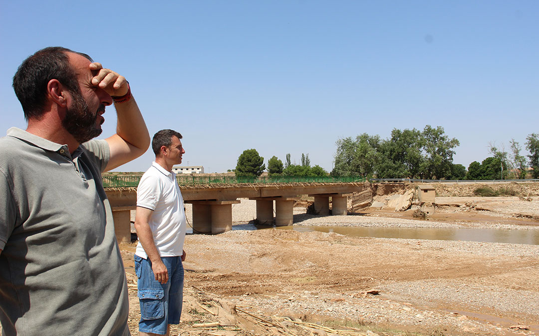 Luis Ezquerra y Álvaro Segundo, alcalde y teniente de alcalde de Vinaceite, junto al puente de La Tejería roto e impracticable, hablando con agricultores al otro lado de la orilla. / B. Severino