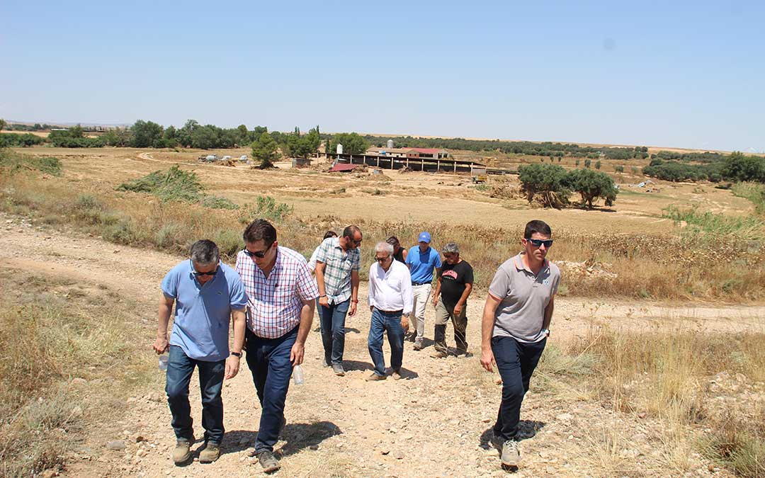 Momento de la visita en Vinaceite con el consejero en el centro conversando con el alcalde y detrás, el ganadero cuya granja (al fondo) quedó arrasada. / B. Severino