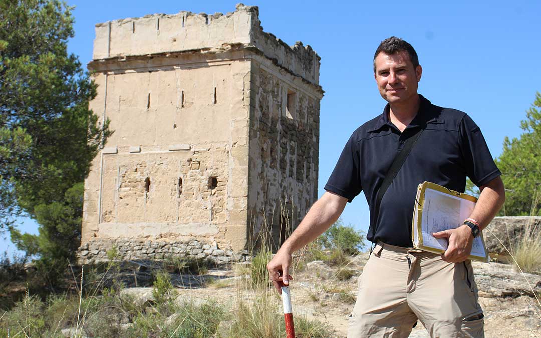 Álvaro Segundo, delante de la Torre del Campamento de Alcañiz de época carlista, con su carpeta y apoyado en el jalón que encargó fabricar en madera al carpintero de Vinaceite en sus inicios. Le sirve para tomar fotos a escala. / B. Severino