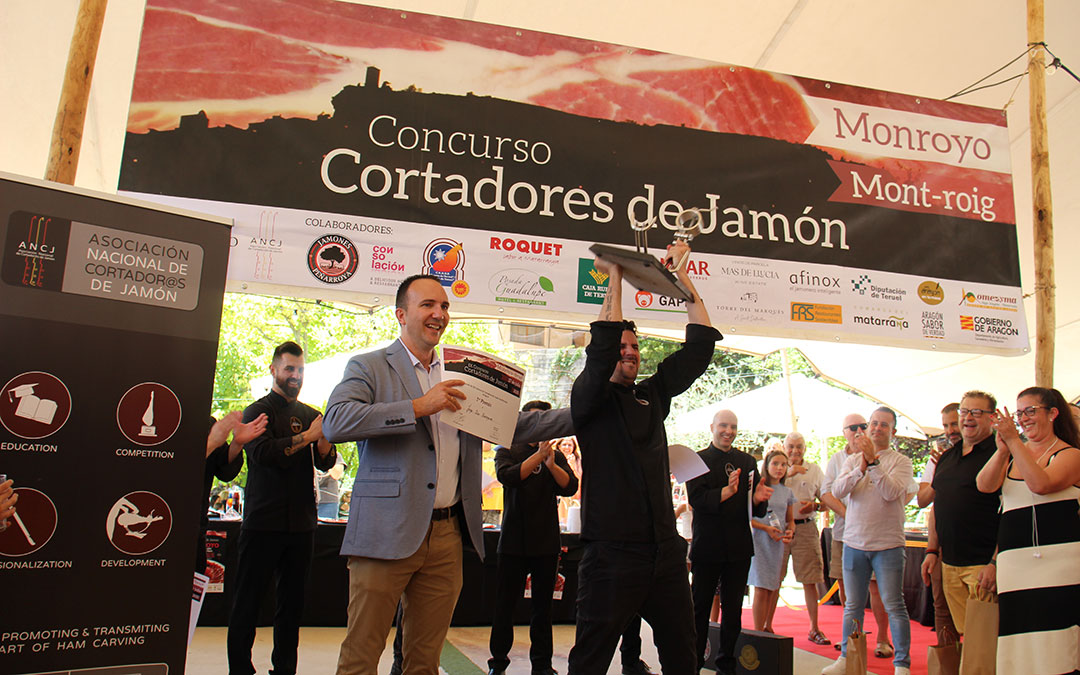 Jorge Díaz levanta su jamonero como campeón en Monroyo en presencia del alcalde, Miguel Gascón, y arropado por los otros seis participantes. / B. Severino