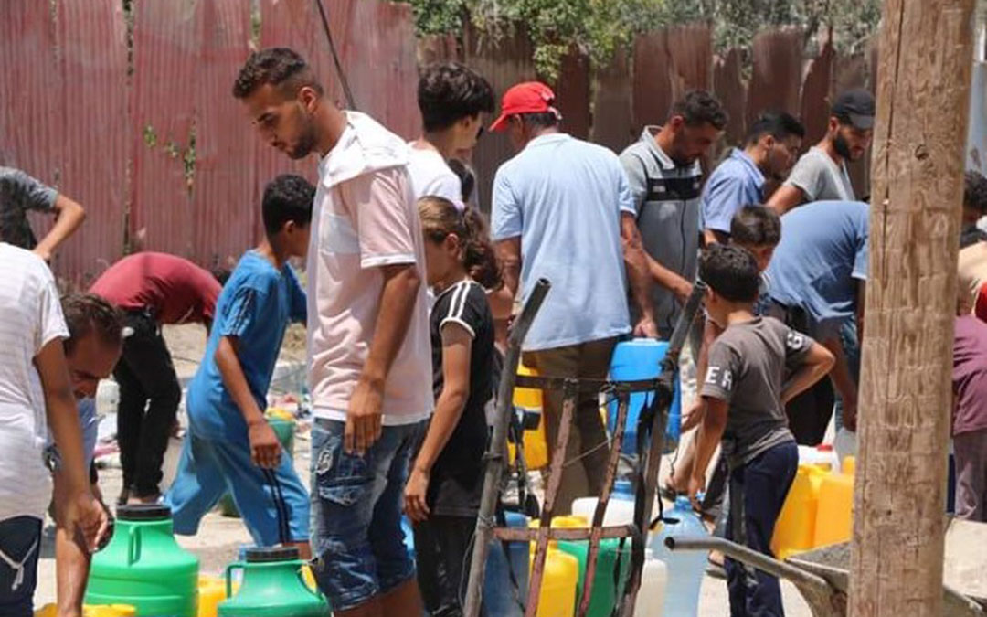 Uno de los hermanos de Fadi en el reparto de agua en el campamento donde sobreviven desplazados. / Archivo familiar