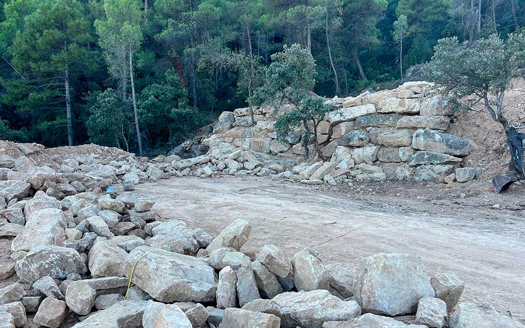 Trabajos previos para rehacer los muros de piedra en los antiguos bancales de cultivo en los que se construirán las masías de 60 metros cuadrados / Torre del Marqués