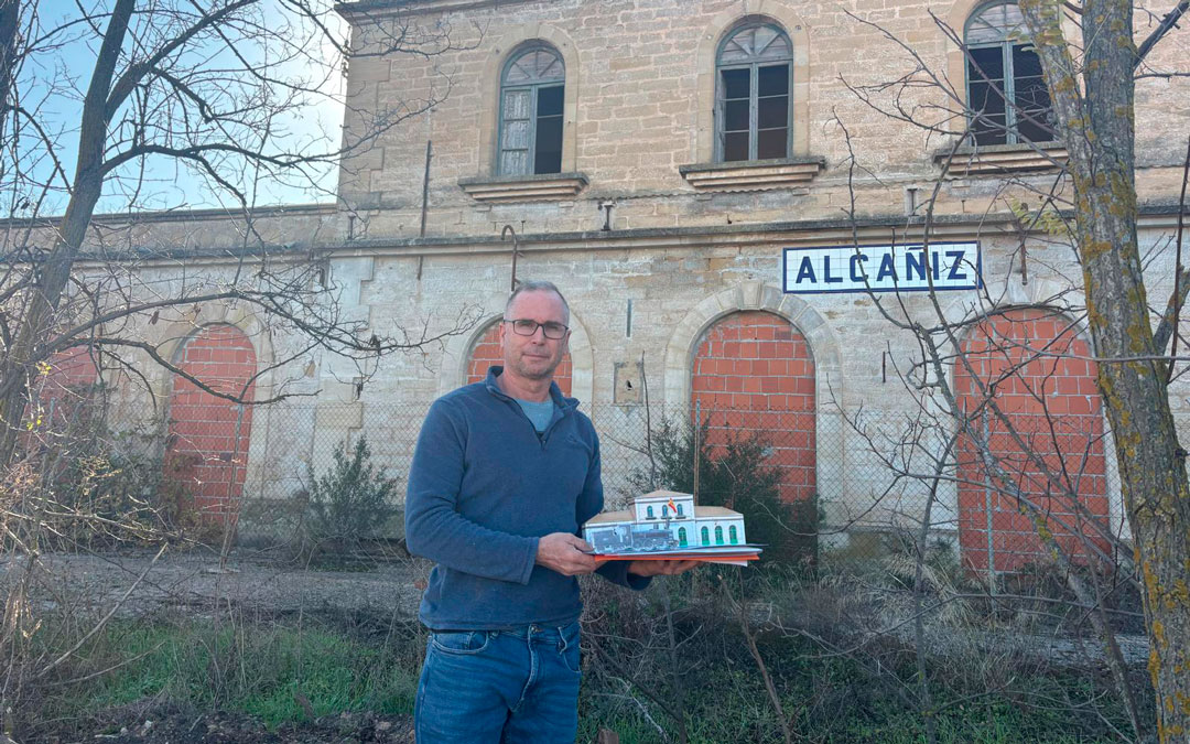El concejal Carlos Andreu muesta el nuevo recortable frente a la antigua estación de tren de Alcañiz./ M.M.R.