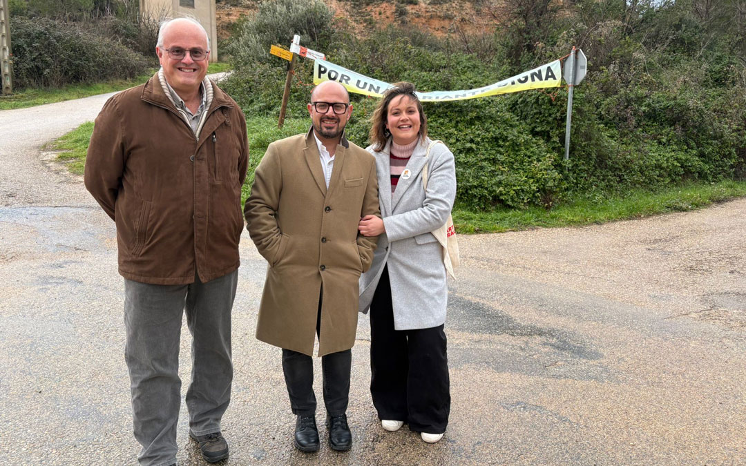 Los tres representantes posan frente a una pancarta que reclama cambios en la variante./ PAR