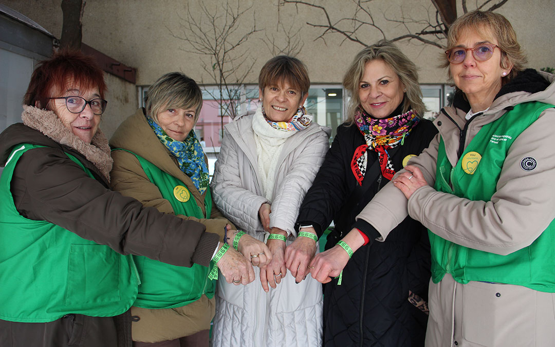 Esperanza Ochoa de Alda, Emilia Esteruelas, Marián Portolés, Carmen Portolés y Yolanda Carretero, de la AECC en las mesas informativas en Alcañiz mostrando las pulseras. Invitan a tomarse fotografías con ellas y subirlas a redes con #elsimboloquehumaniza / B. Severino